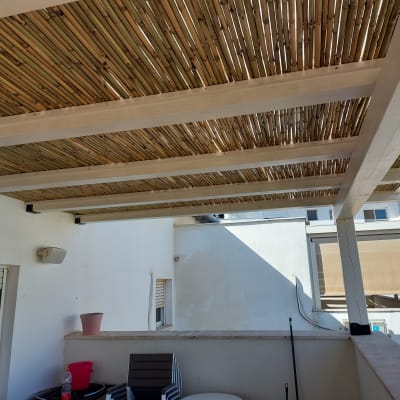 פרגולה מעץ עם גג במבוק על מרפסת