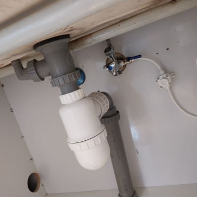 צנרת פלסטיק מתחת לכיור עם ברזים וחיבורים