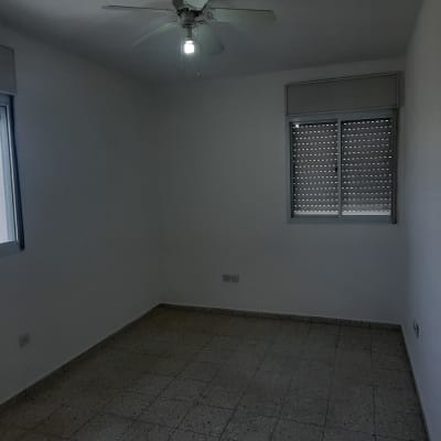 חדר ריק עם חלונות, מאוורר תקרה ורצפת אריחים