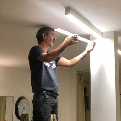 חשמלאי מתקין תאורה על תקרה בעזרת סולם