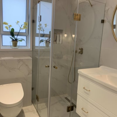 חדר רחצה עם מקלחון זכוכית וברזים מוזהבים