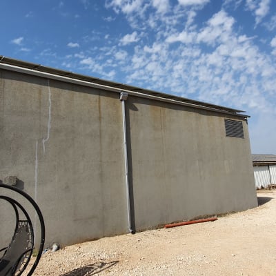 קיר בטון עם מרזב ומתקן מתכת בחצר