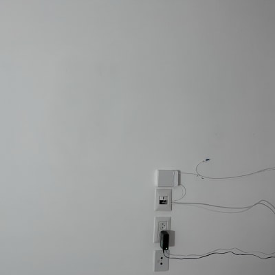 קיר לבן עם שקעים וכבלים מחוברים