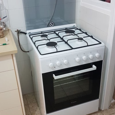 תנור גז לבן עם ארבעה מבערים ומכסה זכוכית