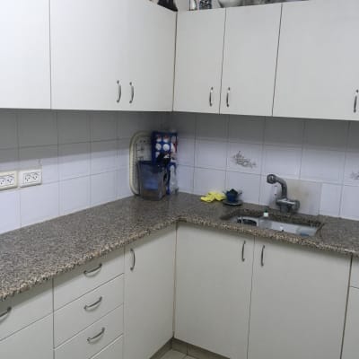 מטבח עם ארונות לבנים ומשטח עבודה גרניט