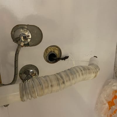 צינור פלסטיק לבן מחובר לקיר עם חיבור מתכת