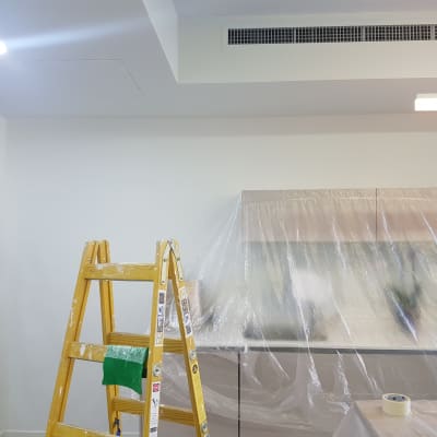 סולם צהוב עם כתמי צבע, קיר מכוסה בניילון