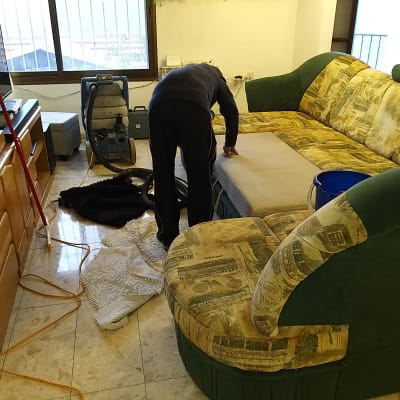אדם מנקה ספה עם מכונת ניקוי וציוד נוסף