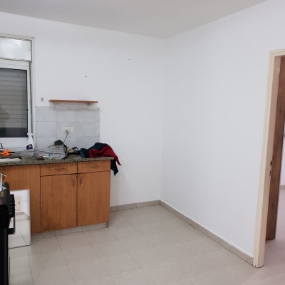 קיר צבוע בלבן עם מדף קטן מעל ארון מטבח