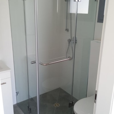 מקלחון זכוכית עם ראש מקלחת וכיור לידו