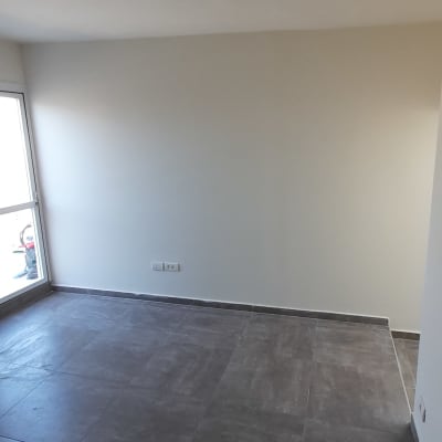 קיר צבוע בלבן בחדר ריק עם רצפת אריחים אפורה