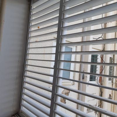 תריסים לבנים עם שלבים אופקיים ליד חלון