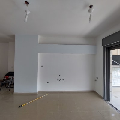 קיר צבוע לבן עם גליל צבע על הרצפה