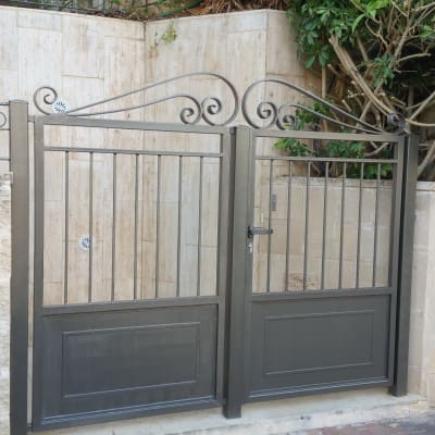 שער מתכת עם עיטורים על רקע קיר אבן