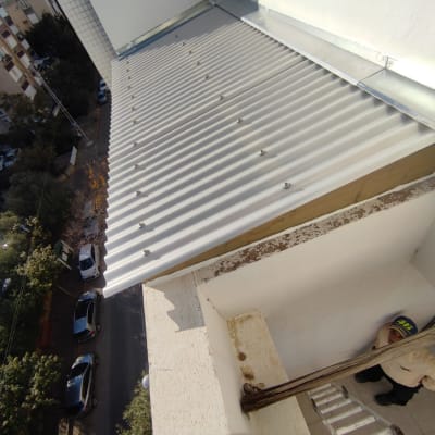 גג מתכת עם ברגים, סולם ואדם למטה