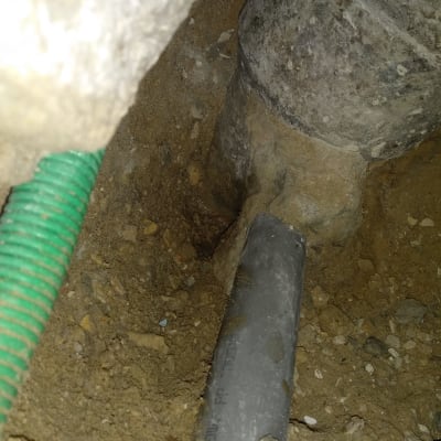 צינור פלסטיק אפור באדמה עם צינור ירוק