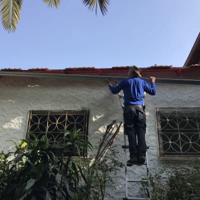 אדם על סולם מתקן מרזב על גג הבית