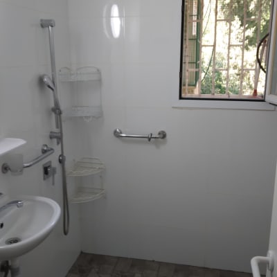 חדר רחצה עם מקלחון, כיור ומדף מתכת