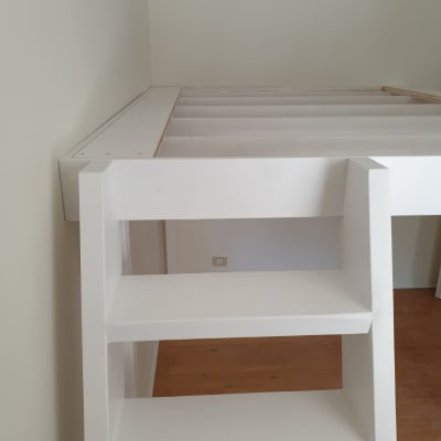 סולם עץ לבן מחובר למיטה מוגבהת
