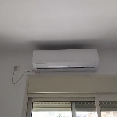 מזגן קיר לבן מותקן מעל חלון