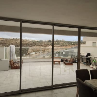 חלונות אלומיניום גדולים במרפסת עם נוף חיצוני