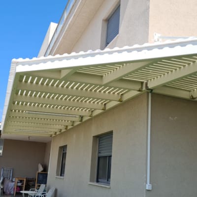 פרגולה לבנה מחוברת לקיר חיצוני של בית