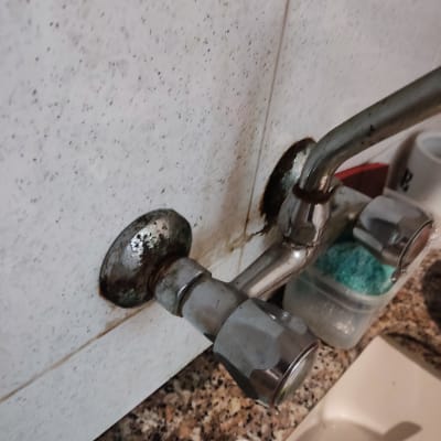 ברז מים עם חלודה על קיר אריחים