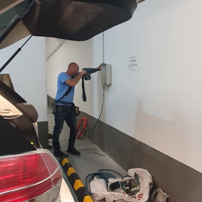 חשמלאי עובד עם מקדחה על קיר חניה