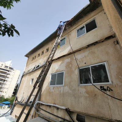 אדם על סולם מתקן גג בניין