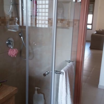 מקלחון זכוכית עם ראש מקלחת ומגבת תלויה