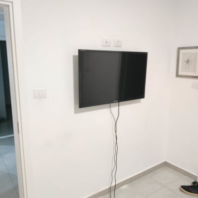 טלוויזיה תלויה על הקיר עם כבלים משתלשלים