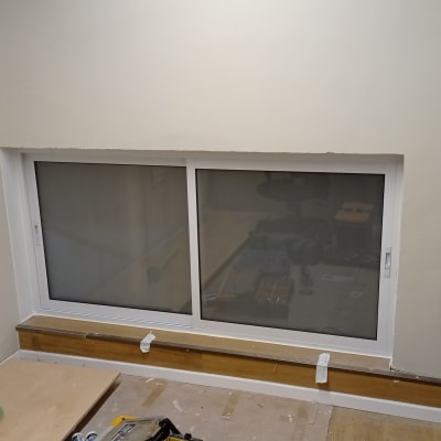 חלון אלומיניום עם מסגרת לבנה מותקן בקיר