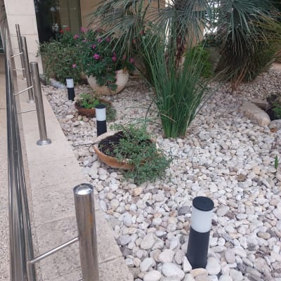 מנורות גינה על עמודים בין אבנים וצמחים