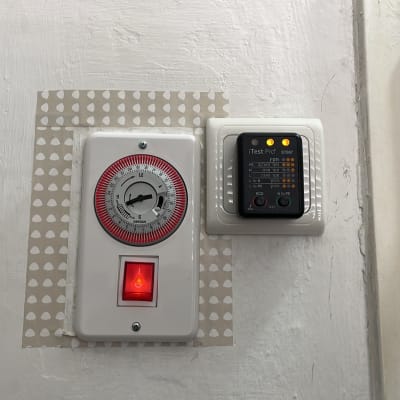 שעון טיימר ומכשיר בדיקת חשמל על קיר לבן