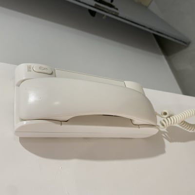 טלפון קווי לבן תלוי על הקיר