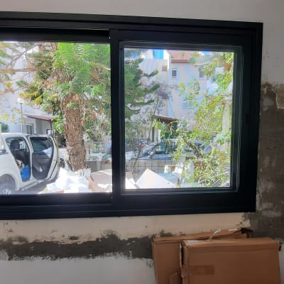 חלון אלומיניום שחור מותקן בקיר בטון