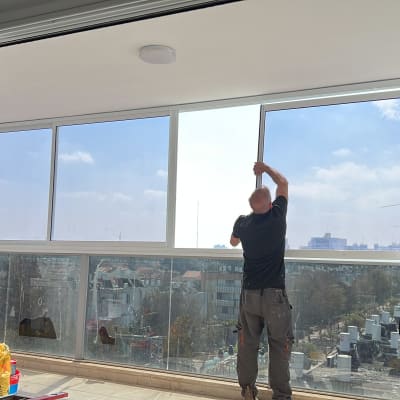 שני אנשים מתקינים מסגרת אלומיניום לחלון גדול