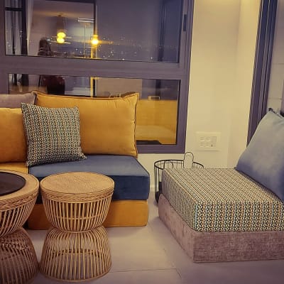 ספה עם כריות צבעוניות ושולחנות קש עגולים