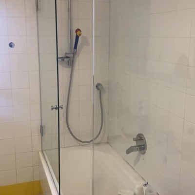 מקלחת עם דלת זכוכית, ראש מקלחת ומוצרים על מדף