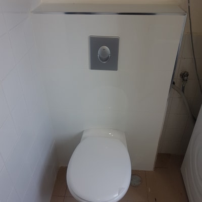 אסלה עם לחצן הדחה על קיר לבן