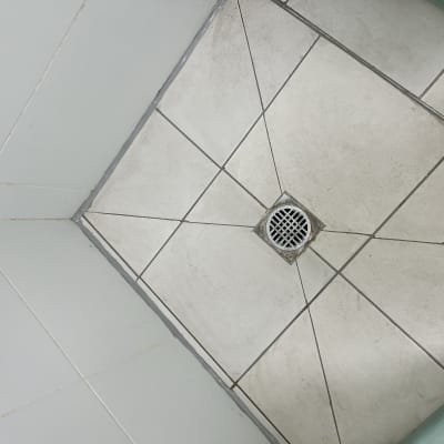 רצפת מקלחת עם רובה סביב האריחים והניקוז