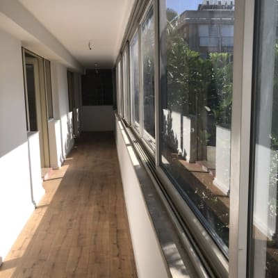 רצפת פרקט עץ במסדרון מואר עם חלונות גדולים