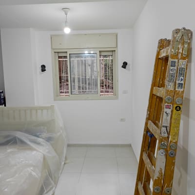 סולם עץ עם כתמי צבע בחדר צבוע לבן