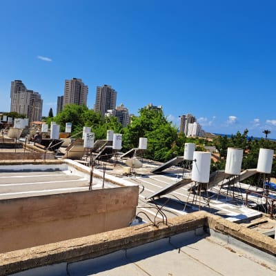 גגות עם קולטי שמש ודודי מים על רקע שמיים כחולים