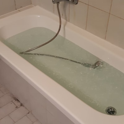 אמבטיה מלאה במים עם ברז ומקלחת יד