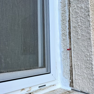 חלון אטום עם חומר איטום לבן על הקיר