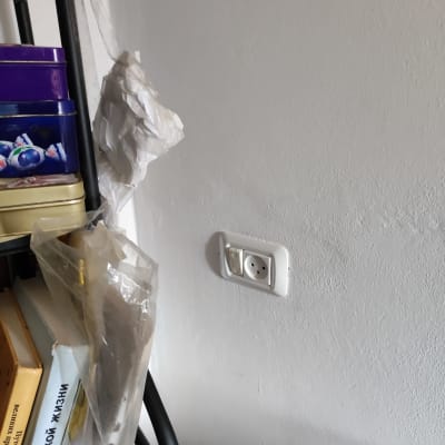 שקע חשמל בקיר לבן ליד מדף עם קופסאות