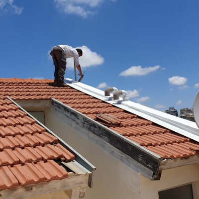 אדם עובד על גג רעפים עם כלי עבודה