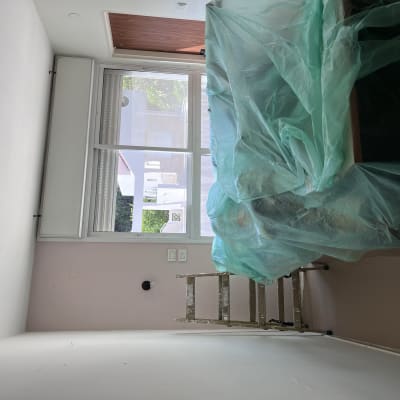 סולם וחפצים מכוסים בניילון ירוק בחדר צבוע