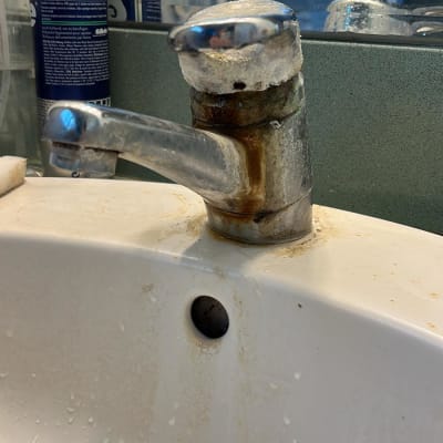 ברז חלוד עם כתמי מים בכיור אמבטיה